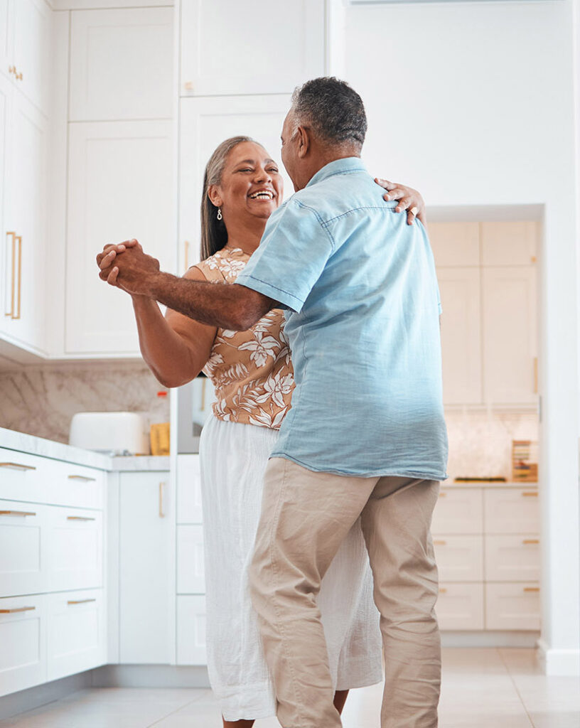 Couple, elderly and dance in kitchen for love, romance and happy together while home in retirement. Senior, man and woman do fun dancing in house for bonding, happiness and care with smile on face